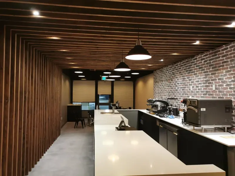 Commercial coffee bar counter with a slatted wood ceiling and brick wall