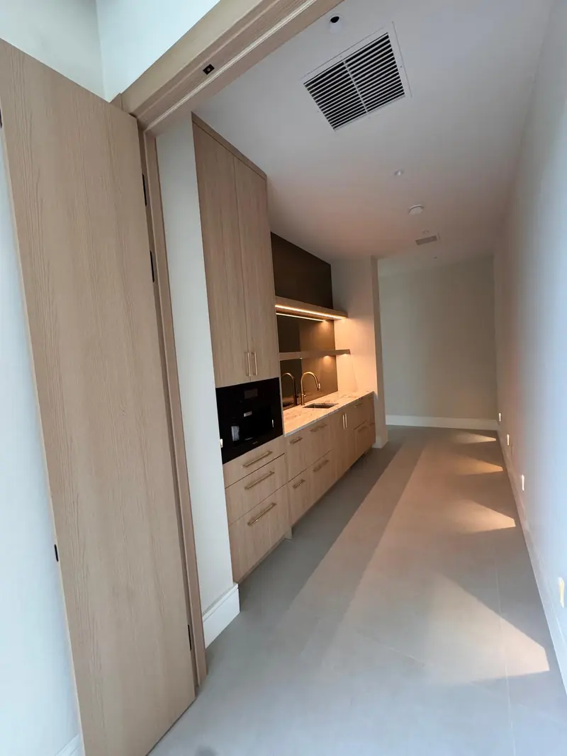 White oak coffee bar with built-in coffee machine along a hallway by Eco Woodwork & Design