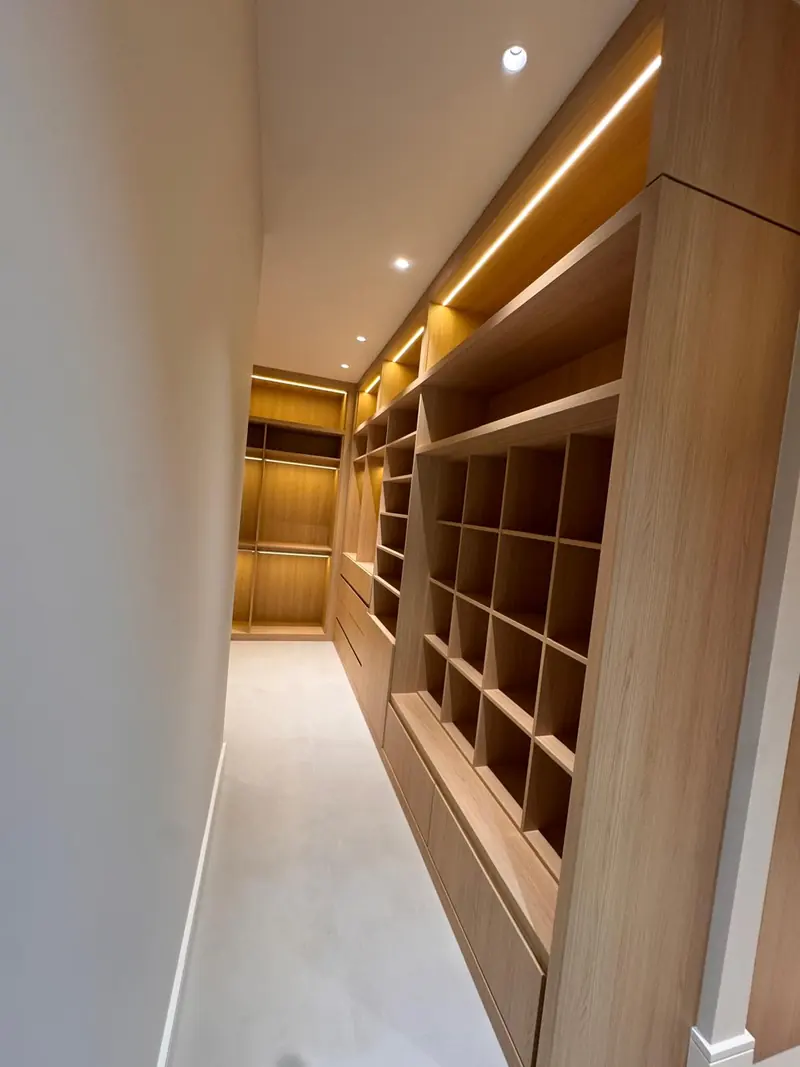 Walk-in closet corridor with lit white oak cubbies by Eco Woodwork & Design