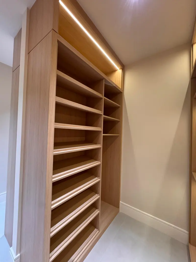 Floor-to-ceiling white oak shoe shelving with LED lighting by Eco Woodwork & Design