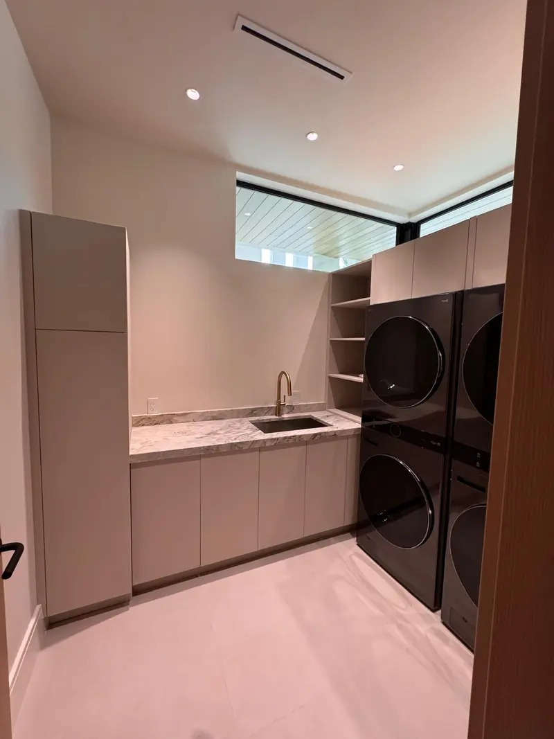 Laundry room with custom cabinetry and stacked washer and dryer by Eco Woodwork & Design