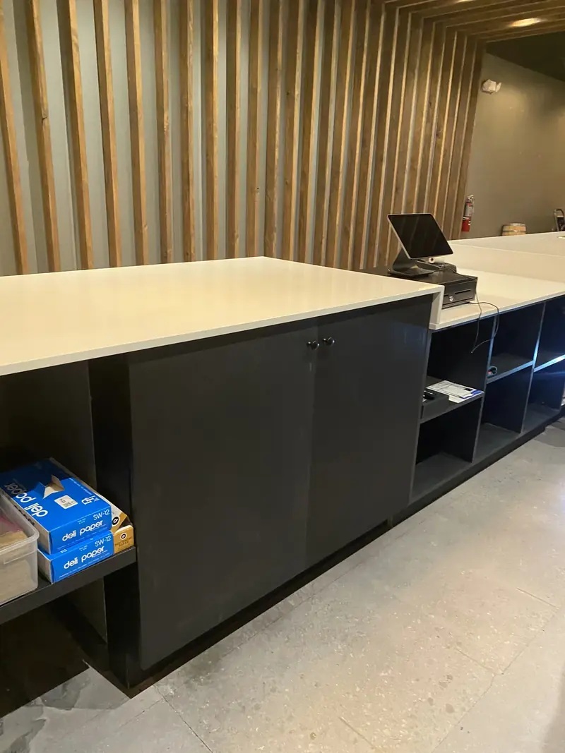 Commercial counter with dark cabinetry in front of a vertical wood-slat wall