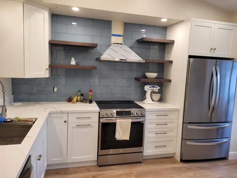 White custom kitchen with open walnut shelving and a blue tile backsplash