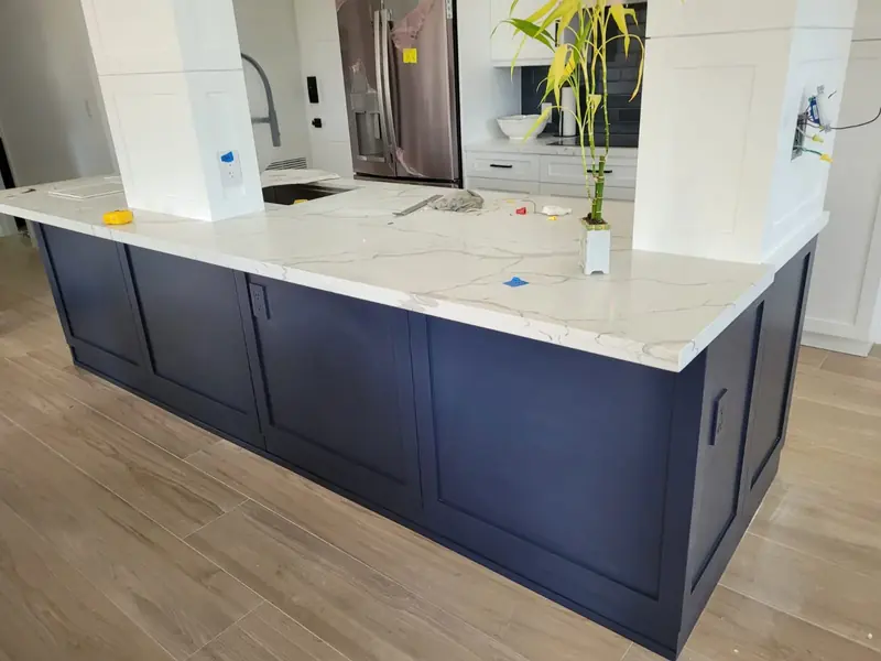 Navy blue kitchen island with shaker doors and a white quartz countertop